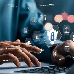 A user using a laptop with cybersecurity icons hovering over his hands